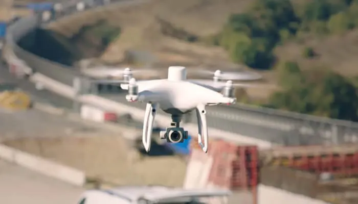 Квадрокоптер DJI Phantom 4 RTK летит над дорогой при съёмке местности