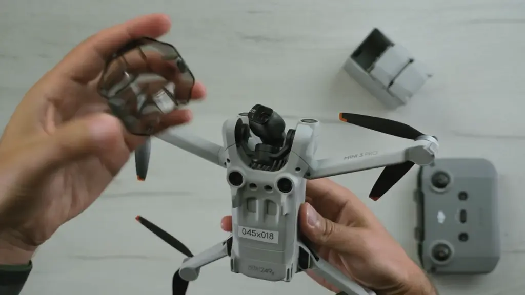 Руки держат DJI Mini 3 Pro, вид сверху на корпус и лучи