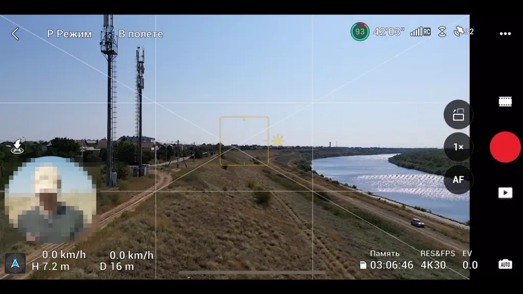 Экран пульта с видом с дрона на башню и реку во время полёта