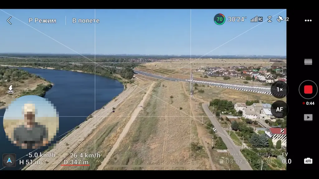 Экран пульта с видом на реку и берег во время полёта дрона